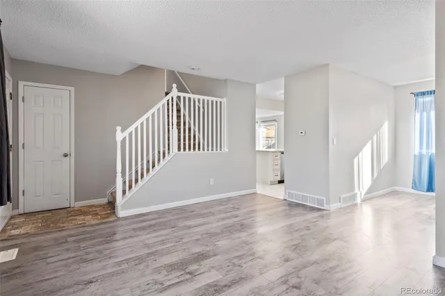 an empty room with wooden floor and windows
