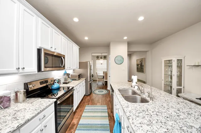 a large kitchen with stainless steel appliances granite countertop a lot of counter space and wooden floor