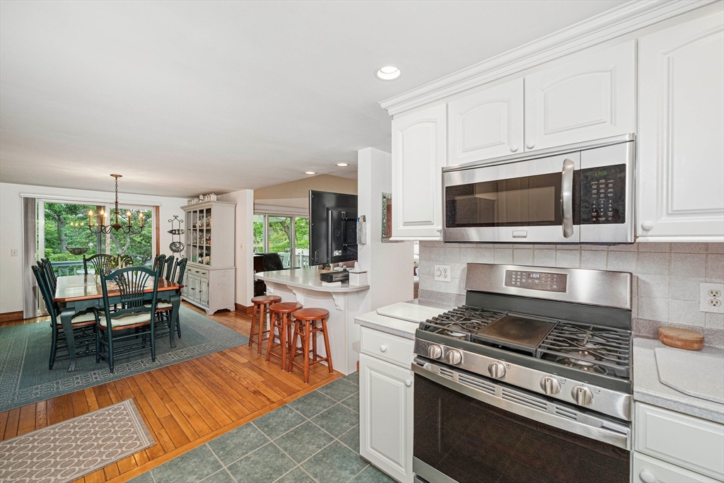74 Fells Pond Road Mashpee, MA 02649 - Photo 9 of 36 a kitchen with stainless steel appliances a stove a sink dishwasher a microwave oven with cabinets and wooden floor