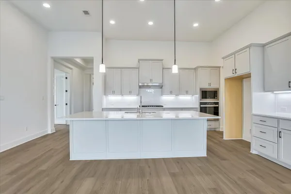 a large kitchen with kitchen island a large window a sink stainless steel appliances and cabinets