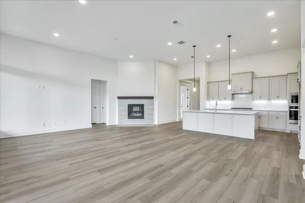 a large kitchen with kitchen island a stove a sink dishwasher and a fireplace with wooden floor