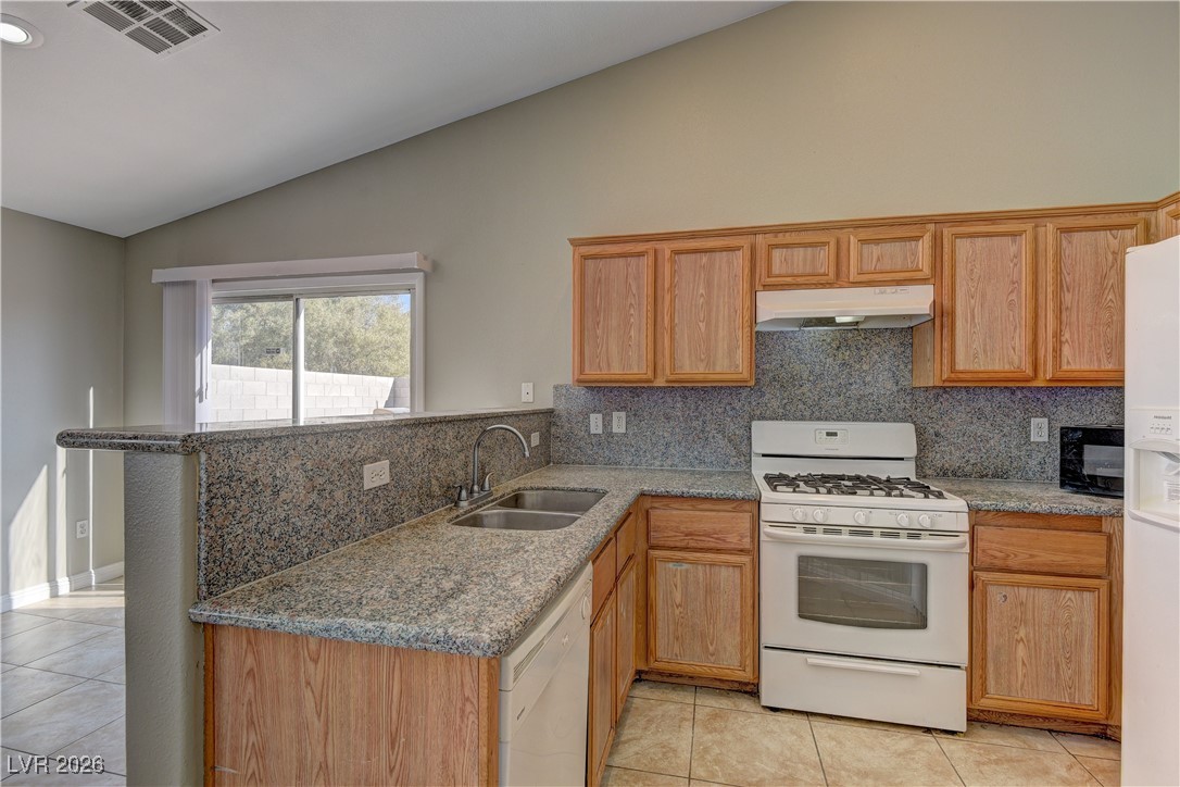 3328 Strawberry Roan Road North Las Vegas, NV 89032 - Photo 6 of 11 Kitchen with white appliances, light tile patterned flooring, light stone countertops, a peninsula, and high vaulted ceiling