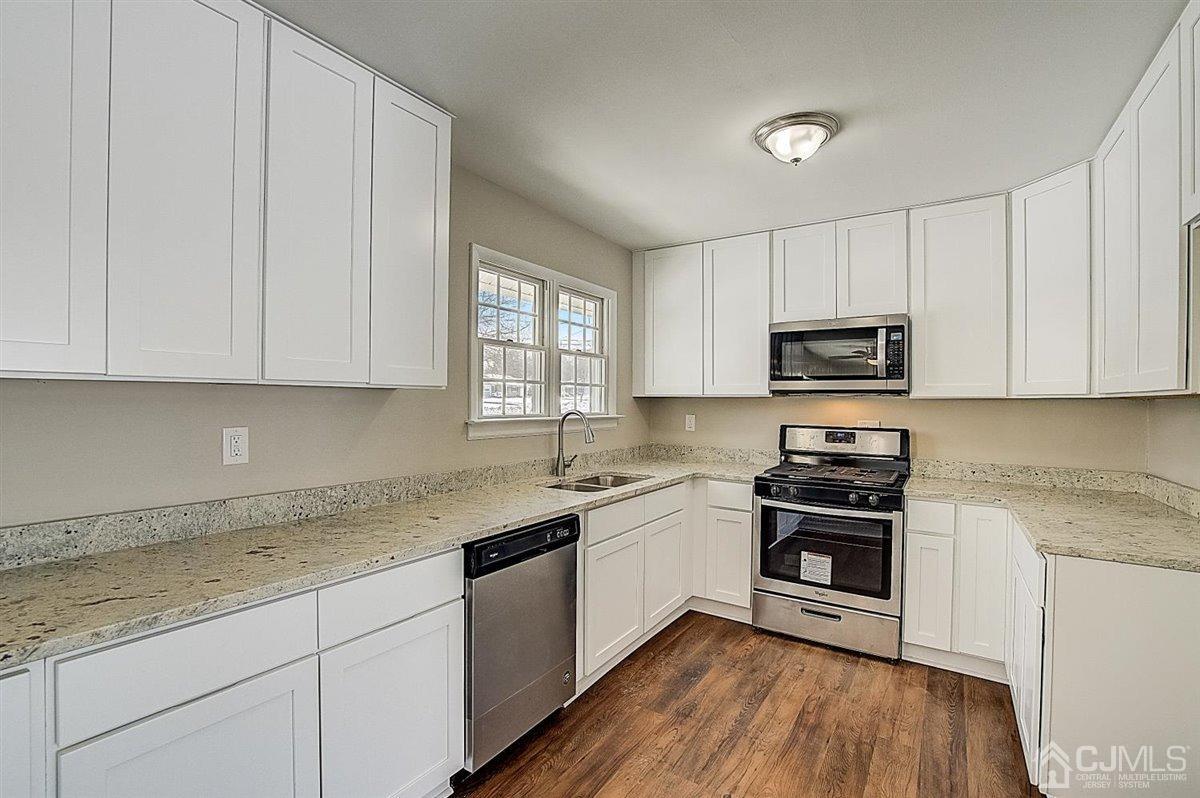 17 Cambridge Road Kendall Park, NJ 08824 - Photo 2 of 28 a kitchen with granite countertop white cabinets sink and stainless steel appliances