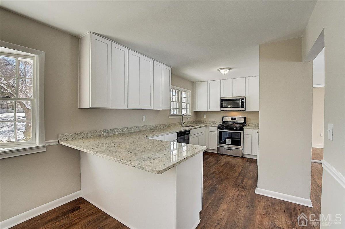 17 Cambridge Road Kendall Park, NJ 08824 - Photo 12 of 28 a kitchen with granite countertop a stove top oven a sink a counter space and cabinets