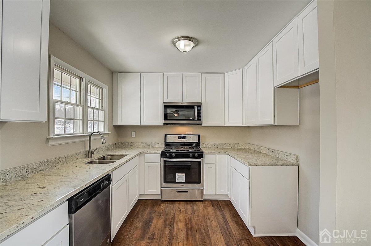 17 Cambridge Road Kendall Park, NJ 08824 - Photo 3 of 28 a kitchen with granite countertop white cabinets and stainless steel appliances