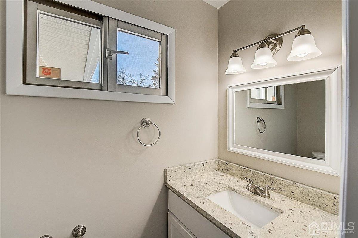 17 Cambridge Road Kendall Park, NJ 08824 - Photo 27 of 28 a bathroom with a granite countertop sink and a mirror