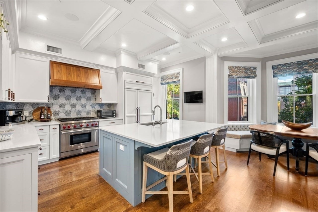 288 Commonwealth Avenue, Unit 3 Boston, MA 02115 - Photo 12 of 25 a kitchen with stainless steel appliances granite countertop a stove top oven a sink a dining table and chairs with wooden floor