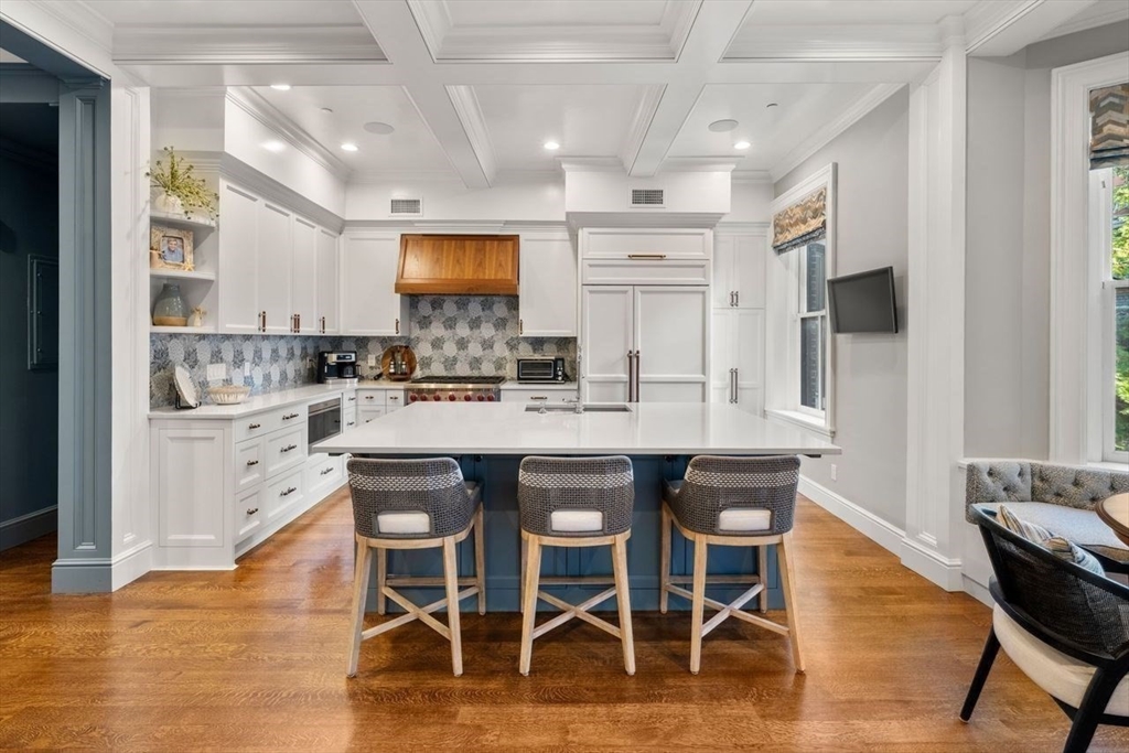 288 Commonwealth Avenue, Unit 3 Boston, MA 02115 - Photo 9 of 25 a kitchen with stainless steel appliances kitchen island granite countertop a dining table chairs and sink