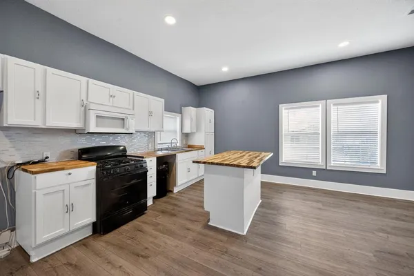 a kitchen with granite countertop a stove a sink and a refrigerator