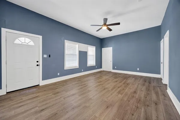 a view of an empty room with wooden floor and a window