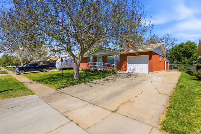 2348 North 770 West Clinton, UT 84015 - Photo 24 of 25 Red brick exterior with white trim, featuring a single-car garage and an accessible ramp leading to the front entry