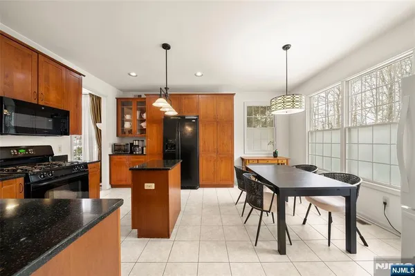 a kitchen with stainless steel appliances granite countertop a sink a stove a refrigerator a dining table and chairs with wooden floor