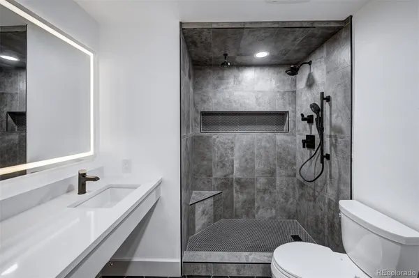 a bathroom with a granite countertop sink toilet and shower