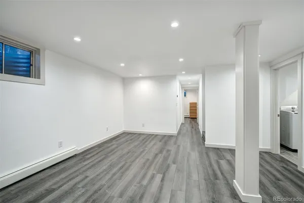 a view of a hallway with wooden floor and a bathroom