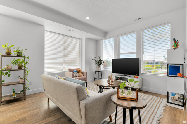 8307 Durham Street Sandy, UT 84070 - Photo 3 of 29 Living room featuring wood-finish flooring, recessed lighting, and multiple large windows with blinds