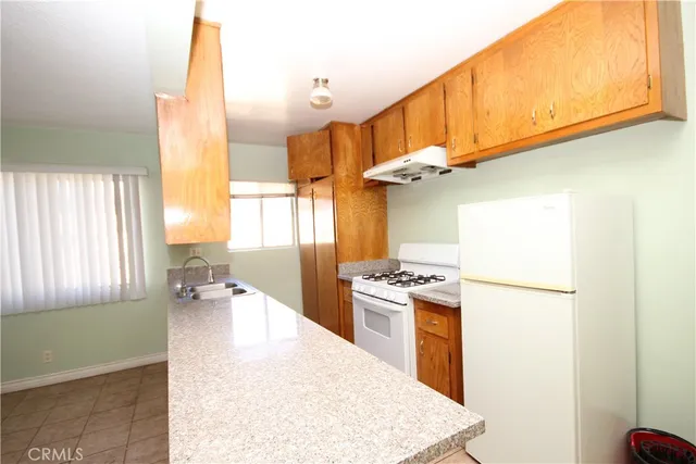 a kitchen with a refrigerator a stove top oven a sink and a window