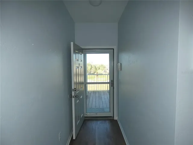 a view of a hallway with wooden floor and a window