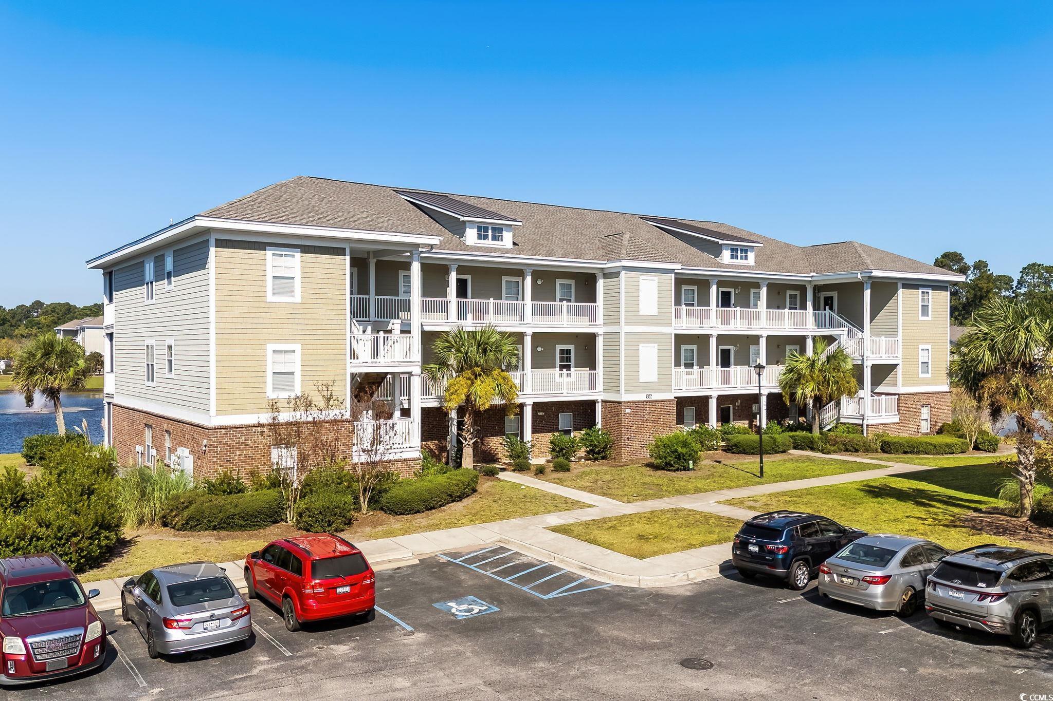 View of apartment building / complex featuring uncovered parking