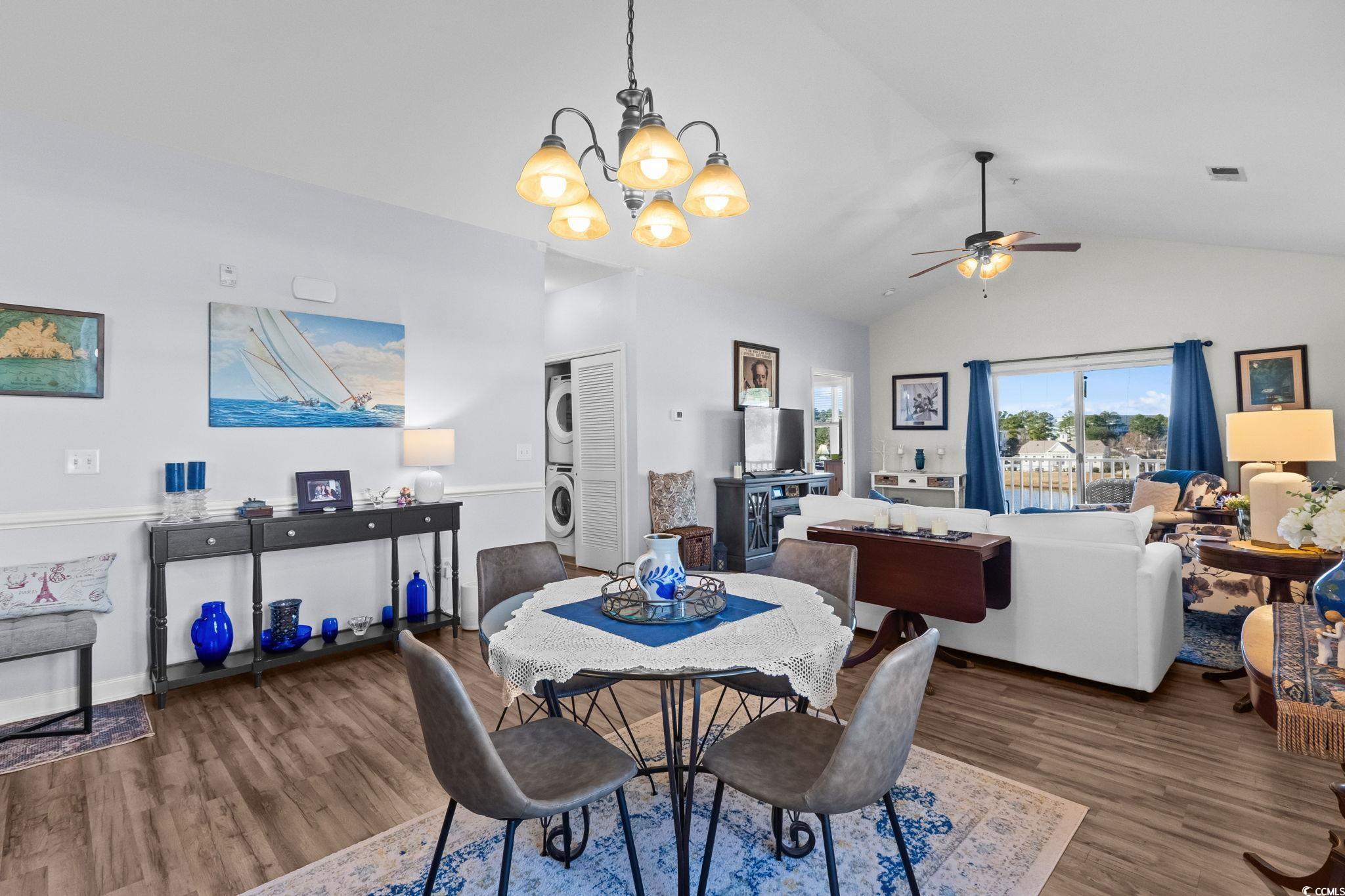 336 Kiskadee Loop, Unit 19O Conway, SC 29526 - Photo 6 of 26 Dining area with stacked washer / dryer, dark wood-style floors, vaulted ceiling, a chandelier, and ceiling fan