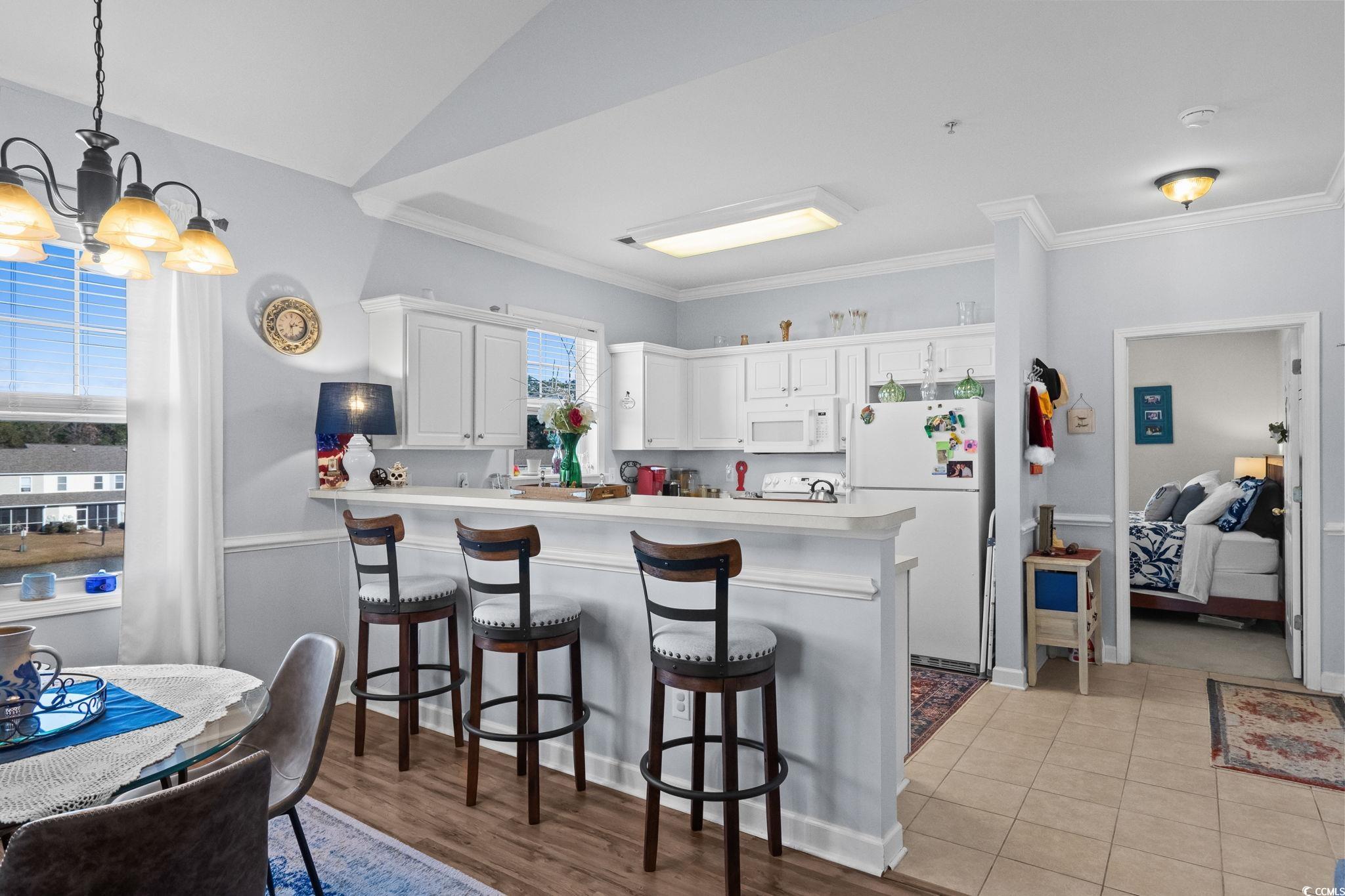 336 Kiskadee Loop, Unit 19O Conway, SC 29526 - Photo 9 of 20 Kitchen featuring light countertops, a breakfast bar, a peninsula, white cabinetry, and white appliances