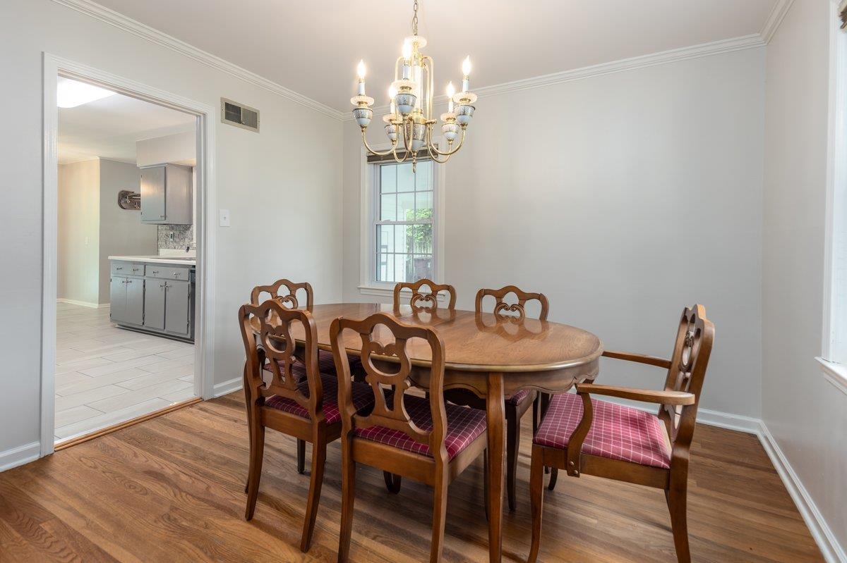 670 Peterson Lake Road Collierville, TN 38017 - Photo 19 of 37 Dining area featuring wood-finish flooring, a brass chandelier, and crown molding