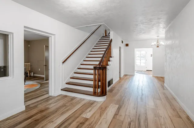 a view of a hallway with wooden floor and stairs