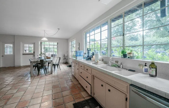a large white kitchen with granite countertop a large window