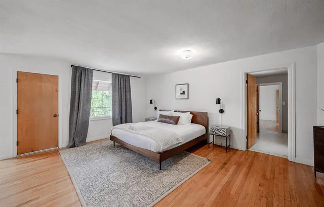 a spacious bedroom with a bed and wooden floor