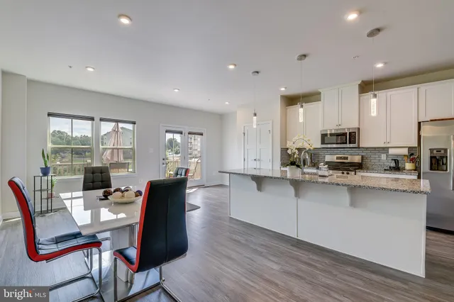 a view of kitchen with stainless steel appliances granite countertop a table and chairs in it