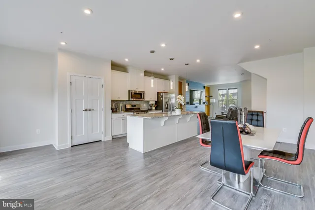 a kitchen with stainless steel appliances kitchen island granite countertop wooden floors and cabinets