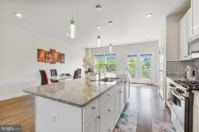 a large kitchen with granite countertop a stove a sink a dining table and chairs