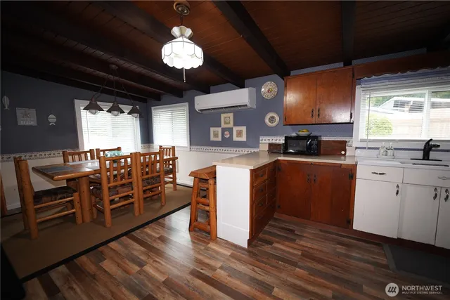 a kitchen with stainless steel appliances a stove top oven a sink a dining table and chairs with wooden floor