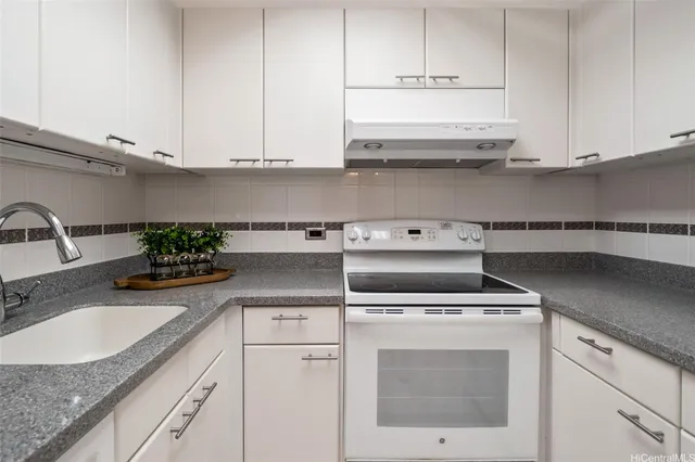 a kitchen with granite countertop white cabinets and white appliances