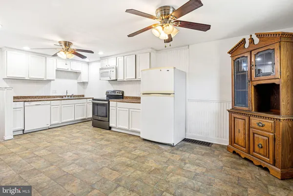 a kitchen with stainless steel appliances granite countertop a refrigerator a oven a sink a stove and white cabinets