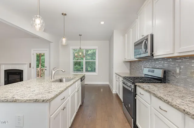 a kitchen with stainless steel appliances granite countertop a sink a stove top oven a counter space and cabinets