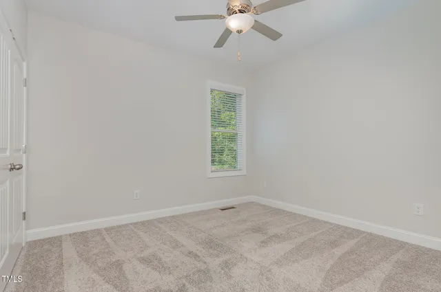 an empty room with a window and a fan