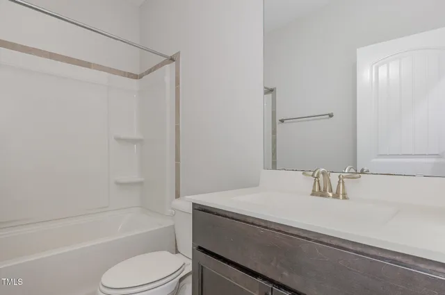 a bathroom with a granite countertop sink toilet vanity mirror and bathtub