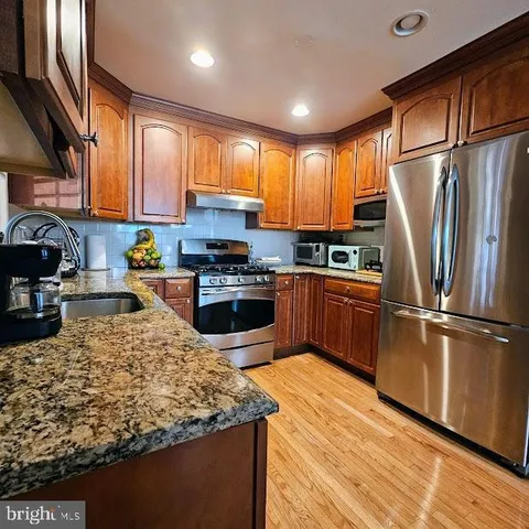 a kitchen with stainless steel appliances granite countertop a refrigerator sink stove microwave and cabinets