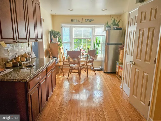 a kitchen with granite countertop a refrigerator a sink dishwasher a stove and white countertops with wooden floor