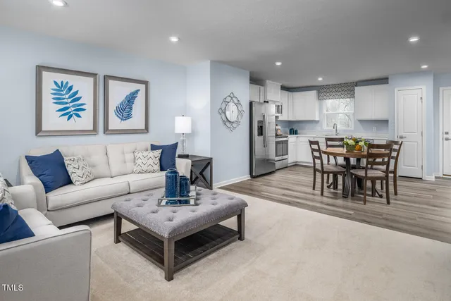 a kitchen with stainless steel appliances a dining table chairs refrigerator and sink