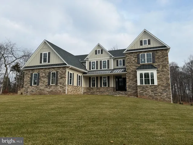 a front view of residential houses with yard and trees in the background