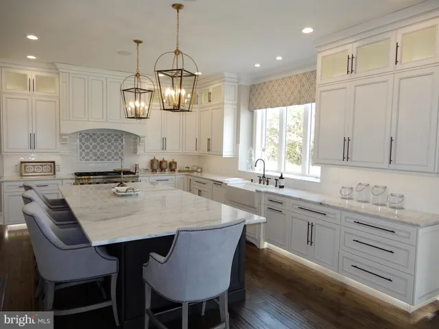 a kitchen with stainless steel appliances granite countertop a sink a stove a refrigerator and island with wooden floor