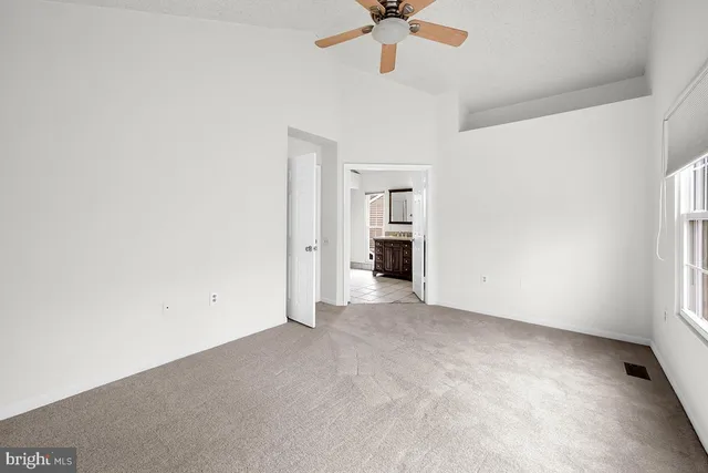 an empty room with a ceiling fan and a window