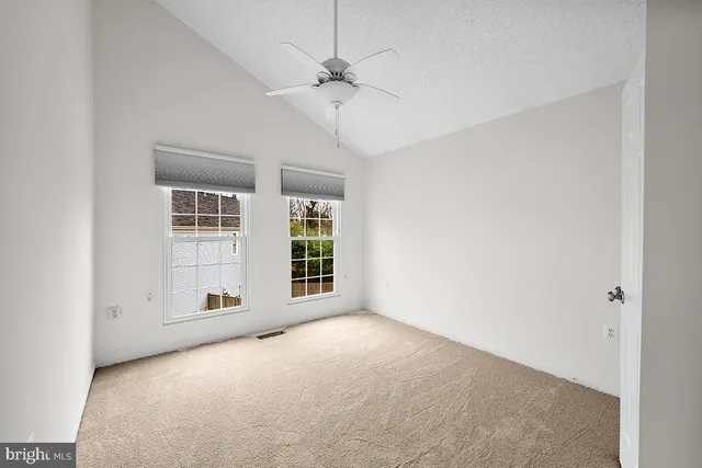 an empty room with windows and ceiling fan