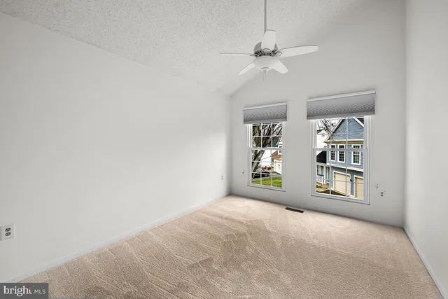 an empty room with windows and ceiling fan