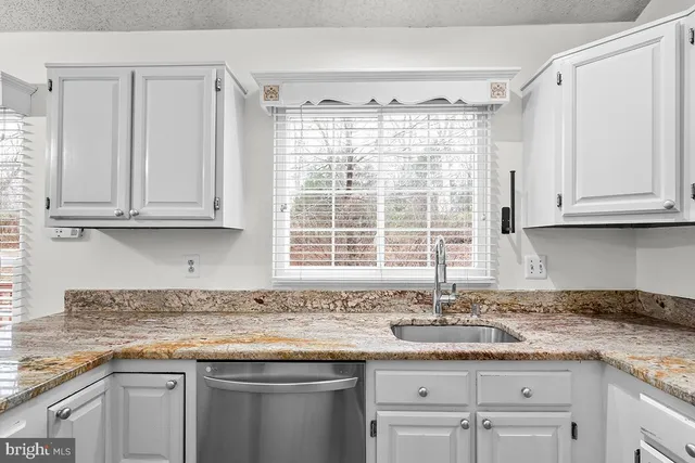 a kitchen with granite countertop white cabinets and a sink