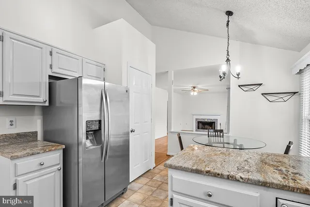 a kitchen with stainless steel appliances granite countertop a refrigerator a oven and white cabinets