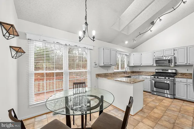 a kitchen with stainless steel appliances granite countertop a stove top oven a sink dishwasher a dining table and chairs with wooden floor