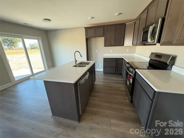 a kitchen with stainless steel appliances granite countertop a sink a stove top oven a counter space and cabinets