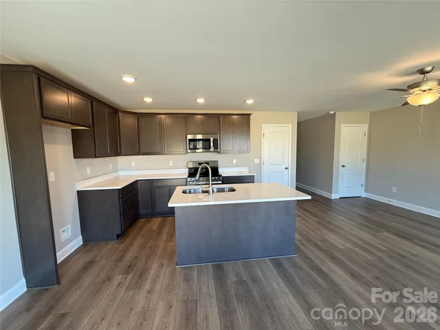 a large kitchen with stainless steel appliances kitchen island granite countertop a large counter top and wooden floors